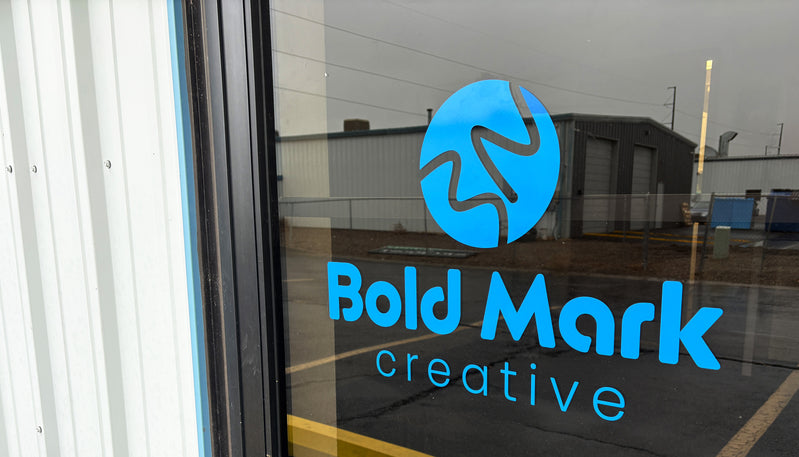 Glass door with 'Bold Mark Creative' logo on a cloudy day
