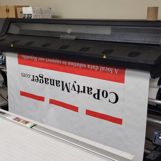 Large printer printing a banner displaying 'CoPartyManager.com' on a white background.