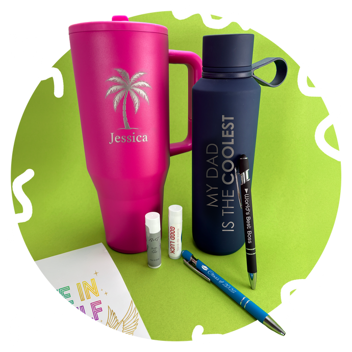 Pink tumbler, navy water bottle, and stationery items on a green background