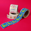 Two rolls of stickers with text and graphics on a pink background