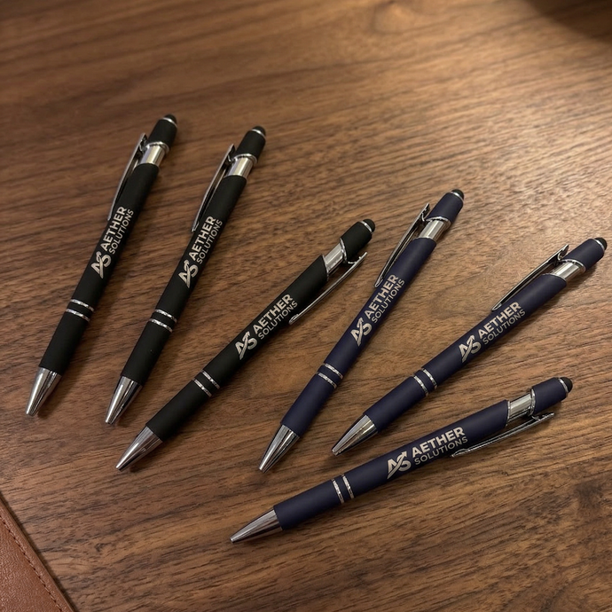 Set of pens with Aether Solutions branding on a wooden surface
