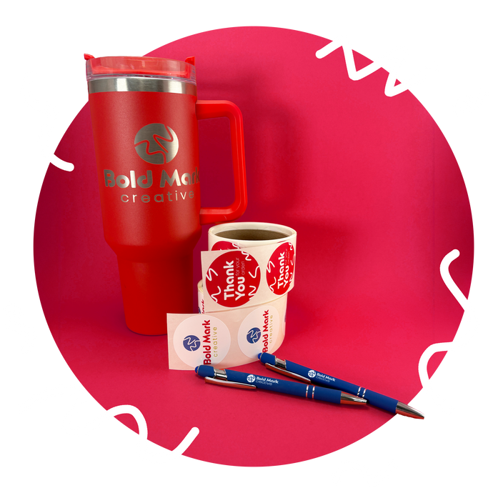 Red tumbler, pens, and stickers with 'Bold Move Creative' branding on a red background