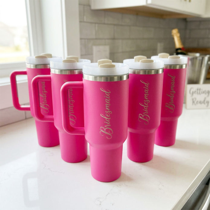 Pink tumblers with 'Bridesmaid' text on a kitchen counter